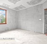 Unfinished room in a family house with a concrete floor and a large window.