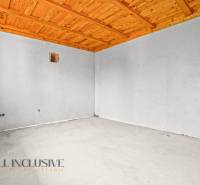 Unfurnished room in a family house with a wooden ceiling and white walls.