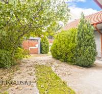 A family house in Bátorove Kosihy with a lush garden and a metal garage door.