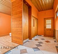 A hallway in a family house with tiles and orange walls, complemented by wooden elements.