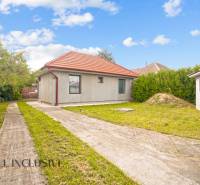 A family house in Bátorove Kosihy, with a lawn, concrete walkway, and a red roof.