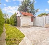 The garden of a family house in Bátorove Kosihy with a path and a gazebo lined with a hedge.