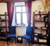 Bookshelves with decorations, chairs, and a window with burgundy curtains in a commercial space.