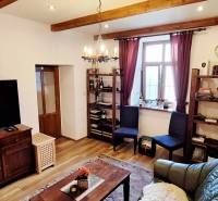 Living room with wood-patterned flooring, a television, shelves, and comfortable furniture.