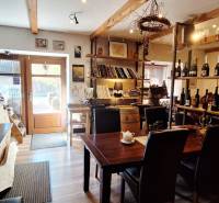 Interior of commercial space with a bar, table, and wine shelves, floor with wooden decor.