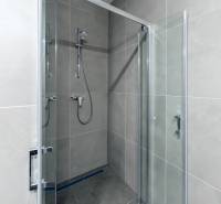 Shower corner with transparent doors and gray tiles in a 3-room apartment.