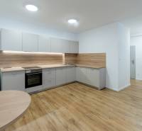 A kitchen in a 3-room apartment with a wooden decor floor and light furniture.