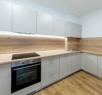 A kitchen in a 3-room apartment with a wood-patterned floor and built-in appliances.