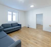 Living room with blue sofas and a table on a floor with a wood decor.