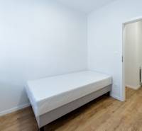 A simple room in a 3-room apartment with a bed and a wooden floor decor.