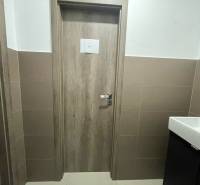 Interior of commercial premises with WC doors, paneled walls, ceramic sink.