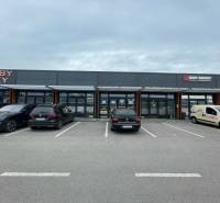 Commercial spaces on Brnianska Street in Trenčín with parking in front of the shops.