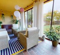 Winter garden with comfortable rattan furniture and a view of the garden in a family house.