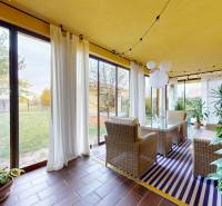 A winter garden in a family house with wicker furniture and a view of the garden.