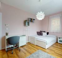 A bedroom in a family house with a desk, a bed, and a floor with a wooden decor.