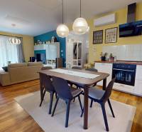 Dining room and kitchen in a family house with a wood-patterned floor, light-colored walls, and tiles.
