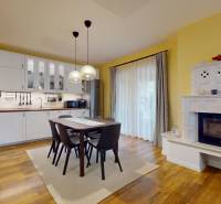 Kitchen and dining room in a family house with a wood-patterned floor and a fireplace.