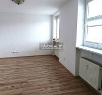 A bright room with wood-patterned flooring in a studio apartment and a large window.