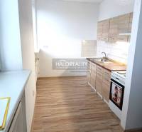 The kitchen of a one-room apartment with a kitchen unit on a floor with a wooden decor.