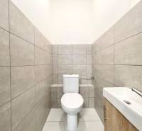 A toilet with a sink and gray tiles in an office interior.