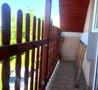 A balcony with a view in a cottage in Hontianske Trsťany. Wooden railing and tiled floor.