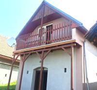 A cottage in Hontianske Trsťany with a wooden balcony and a satellite dish.