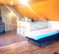 Interior of a cabin with a fireplace, a bar counter, and a floor with a wooden decor.