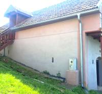 A cottage in Hontianske Trsťany with an outdoor staircase, lawn, and satellite dish.