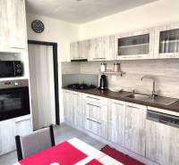 A kitchen in a 2-room apartment with a wooden decor and a red refrigerator.
