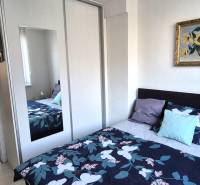 A bedroom with a colorful bed and wardrobe in a 2-room apartment, leading to the living room.