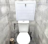 A toilet in a 2-room apartment with tiles in light shades and geometric details.