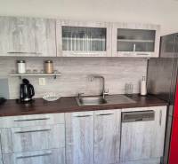 A kitchen in a 2-room apartment with a red refrigerator and a wooden-patterned floor.