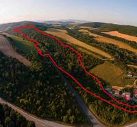 Aerial view of agricultural and forest land near Rokycany surrounded by greenery and a road.