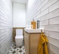 A narrow bathroom with tiles, a toilet, and a sink in a 3-room apartment.