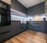 A kitchen in a 3-room apartment with dark cabinets and a wooden-patterned floor.