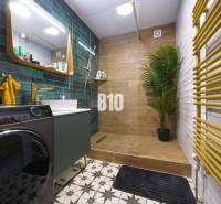 Bathroom in a 3-room apartment with a sink, washing machine, green tiles, and a floor with a wooden decor.