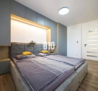 A bedroom in a 3-room apartment with a bed, wardrobes, and a floor with a wooden decor.