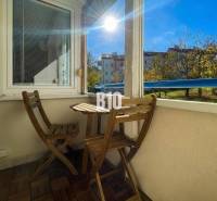 Balcony of a 3-room apartment in Nitra with wooden furniture and a view of greenery.