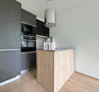 A modern kitchen in a 2-room apartment with wooden flooring and a dark cabinet.