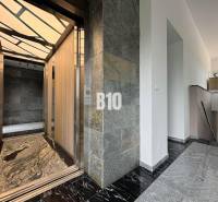 Entrance area and elevator in a 2-room apartment with marble flooring and modern lighting.