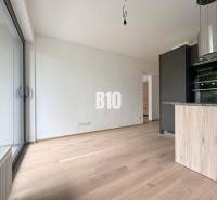 A bright interior of a 2-room apartment with large windows and wooden flooring.