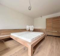 Bedroom in a 2-room apartment with a wooden bed and a wardrobe on a wooden floor.