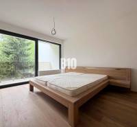 Bedroom in a two-room apartment with wooden flooring and a large window to the terrace.