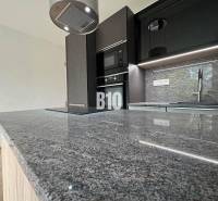A kitchen in a 2-room apartment with a marble countertop and modern equipment.