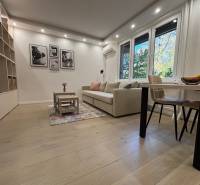 Living room in a two-room apartment, large sofa, table, wooden decor flooring.