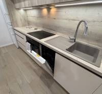 Corner kitchen in a 2-room apartment with a dishwasher and flooring with a wooden decor.