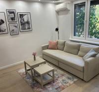 Living room in a 2-room apartment, with a sofa, tables, and photographs on the wall.