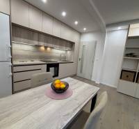 A kitchen in a 2-room apartment with a wood-patterned floor and built-in appliances.