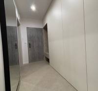 Entrance hallway of a 2-room apartment with white cabinets and a mirror on the wall.