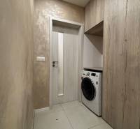 Laundry room in a 2-room apartment with tiles and a washing machine.